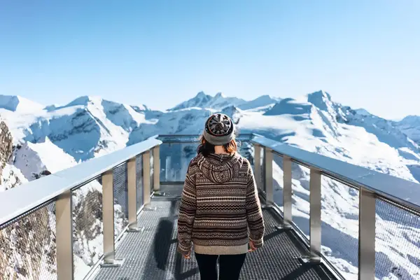 A woman overlooks a snowy mountain in Austria from a viewing platform