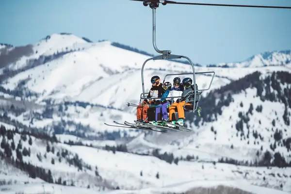 Two adults and two children ride a chairlift in Utah