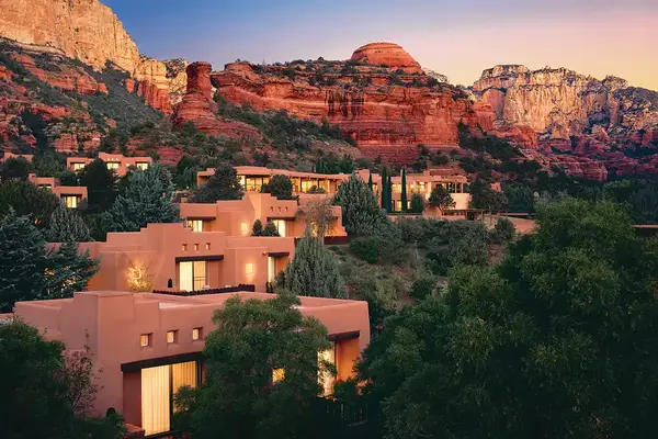 Scenic view of a desert resort surrounded by rocky cliffs and vegetation, featuring terracotta-colored buildings and trees
