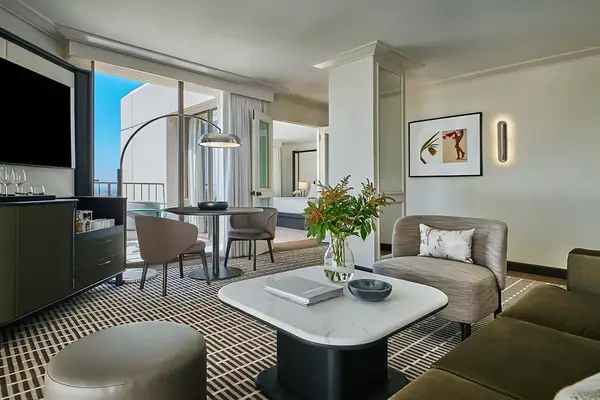 A stylishly furnished living room with seating, a table, and a view of a balcony in a resort