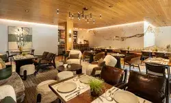 Indoor view of a stylish dining area with arranged tables and chairs modern decor and a bar in the background