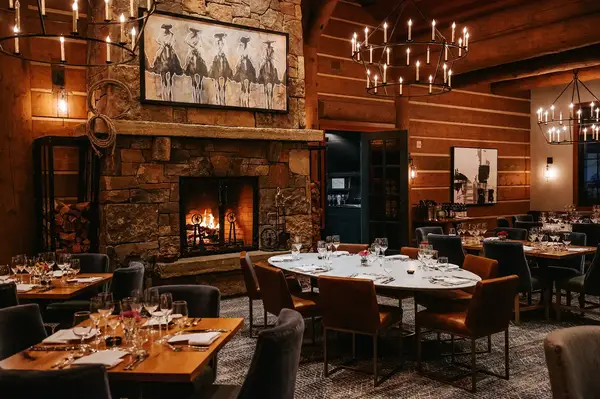Rustic dining room with a fireplace wooden walls and decorated tables
