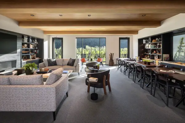 A large living space with seating bookshelves and windows overlooking nature