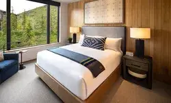 A cozy bedroom with a modern design featuring a bed nightstands and a large window overlooking green foliage