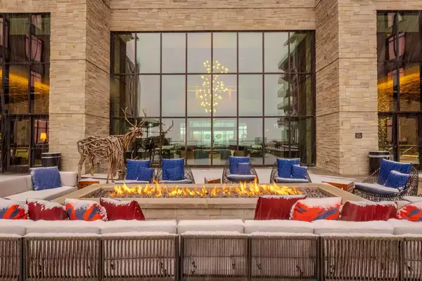 firepit with blue lounge chairs around and a large glass window behind