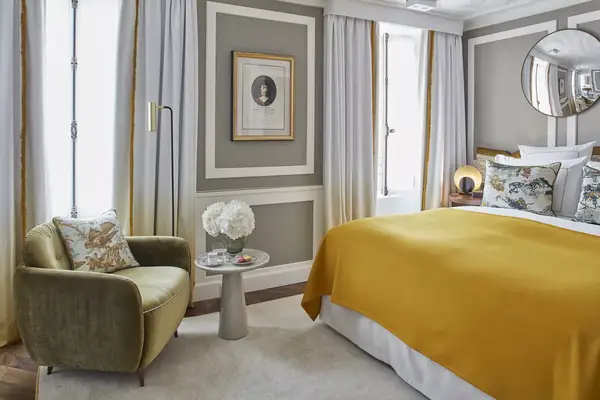 A hotel room with a yellow bedspread and grey walls