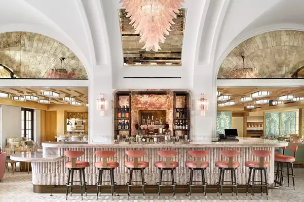 interior of a bar with pink accent chandelier and barstools and white walls