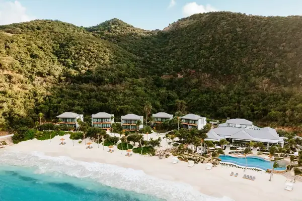 aerial view of resort houses and pool surrounded by lush green mountains at the waterfront