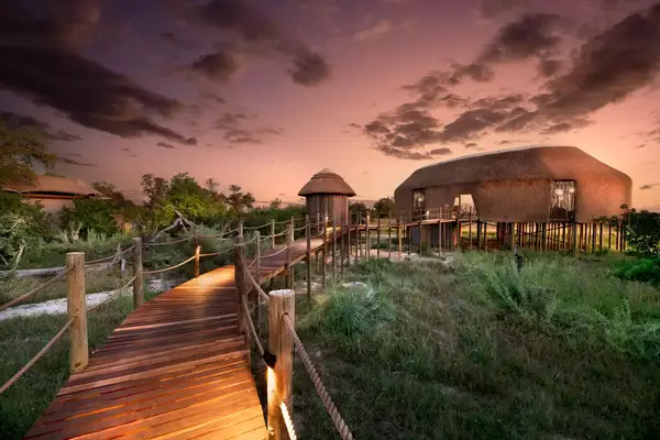 Pink skies and clouds over a luxury safari camp building in Botswana