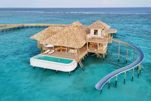 hut sitting on water with a water slide leading into the ocean and outdoor pool attached