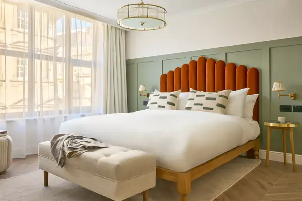 A guest room with an orange headboard in London