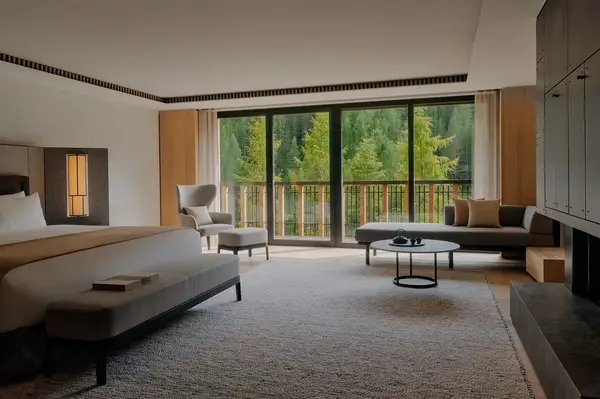 Upscale hotel room with a bed seating area and large windows overlooking trees