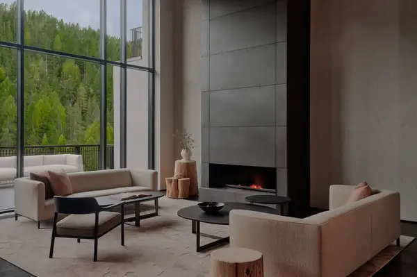 Modern lounge area with sofas fireplace and large windows overlooking greenery