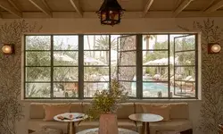 A hotel lounge area facing window panels overlooking an outdoor pool area