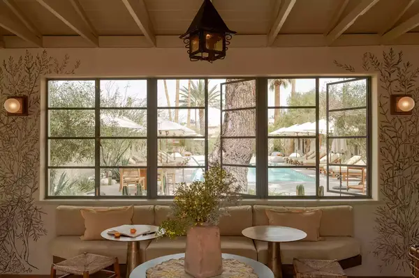 A hotel lounge area facing window panels overlooking an outdoor pool area