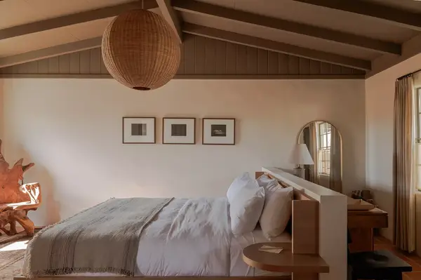 Hotel room with a neatly made bed, framed photographs on the wall, and a wooden ceiling beam structure