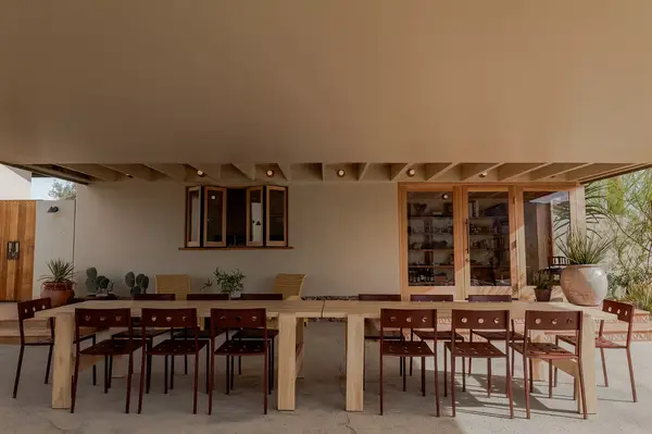 Outdoor dining setup under a shaded terrace by a modern building