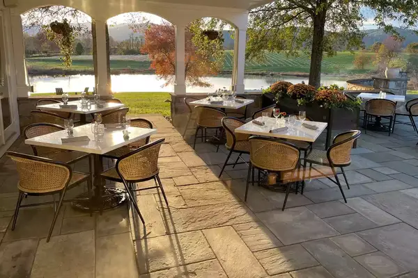 View of outdoor dining patio facing a pond and mountains at Blue Rock in Washington, Virginia 