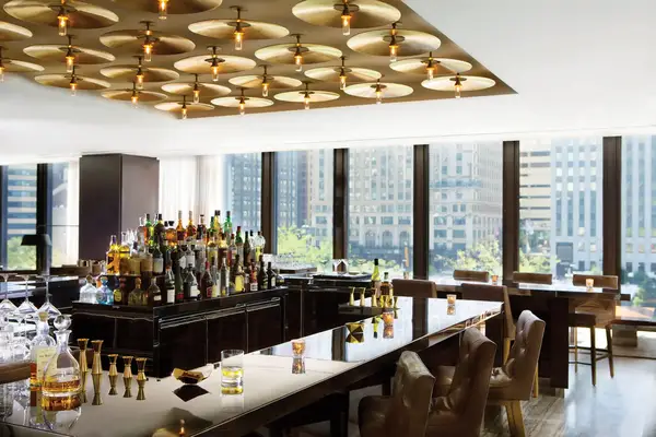 Elegant bar area with a variety of bottles and city views through large windows