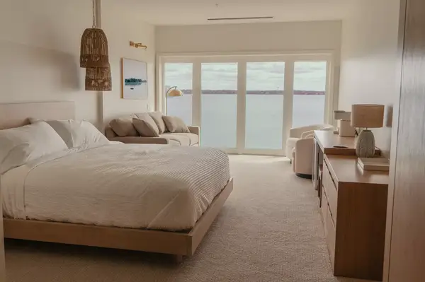 Hotel guest room with a large bed, seating area, and windows overlooking a body of water