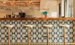 A bar counter with four stools in an empty space, geometric tile design on the bar front