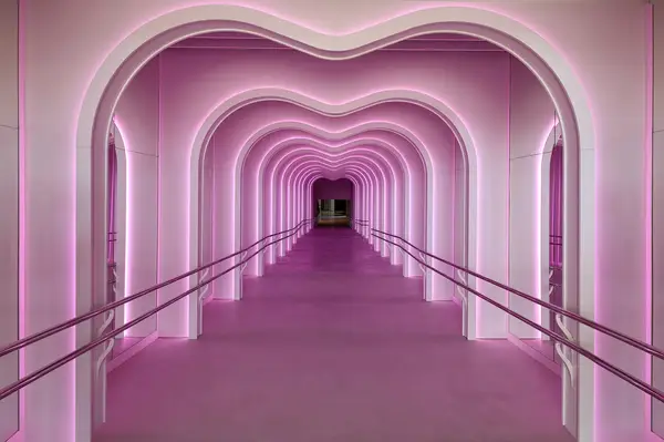 A brightly lit, futuristic tunnel with arching frames leading into the distance