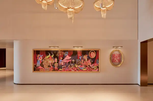 Artwork featuring a lively scene with vibrant characters hung on a wall in a modern interior space