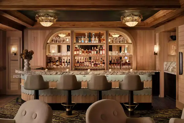 interior view of barstool with warmly lit mirror bar with many bottles