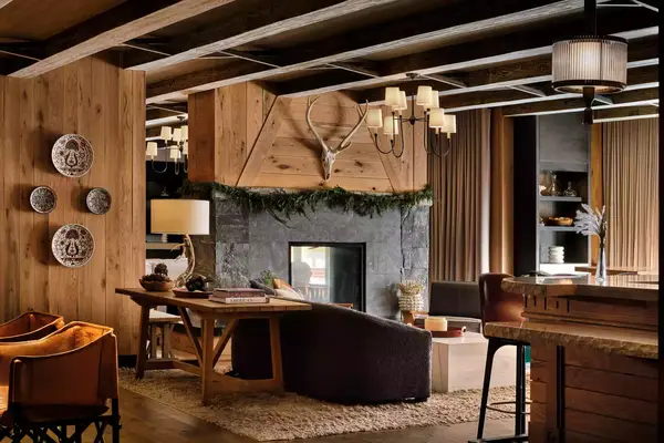 small lobby area with wooden panal walls and a black stone fireplace with a deer head over it