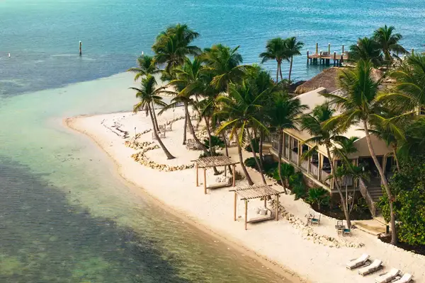 Aerial view of Little Palm Island Resort, beachfront with palm trees, cabanas, and a dock extending into the water.