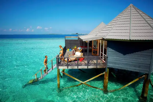Couple entering water from bungalow