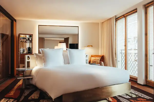 A bedroom with a bed, mirror, and large windows, modern design focus