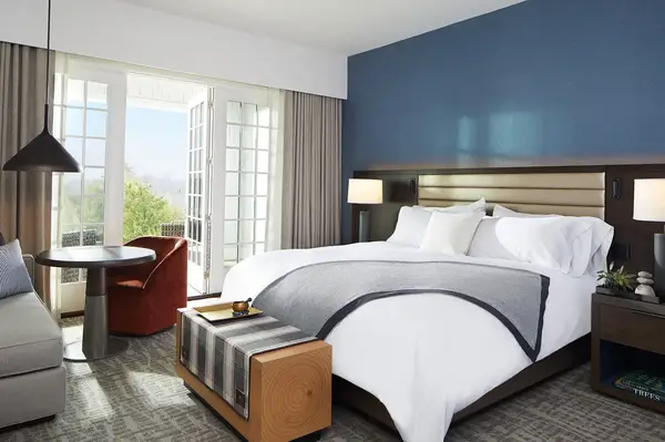 Elegant bedroom with a bed, side tables, a small dining table, and an open balcony view