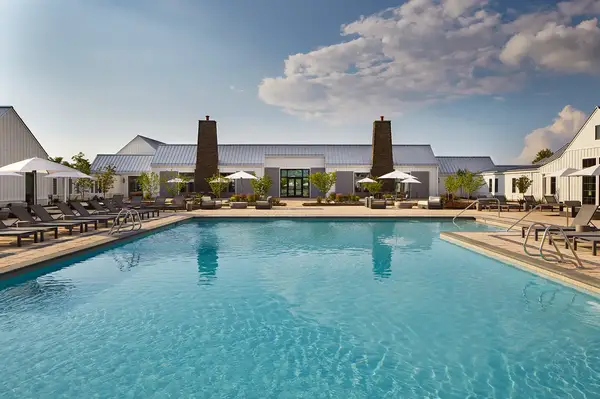 Outdoor pool area with deck chairs and a large building in the background