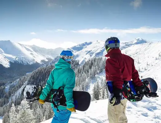 Two snowboarders standing at the summit of Taos Ski Valley, New Mexico