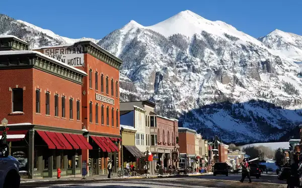 Storefronts with snow-capped mountains in the background at Telluride Mountain Resort