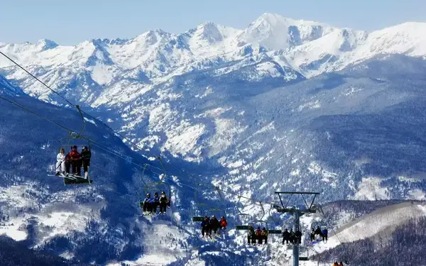 Skiers and snowboarders on three-person lifts at Vail Resort.