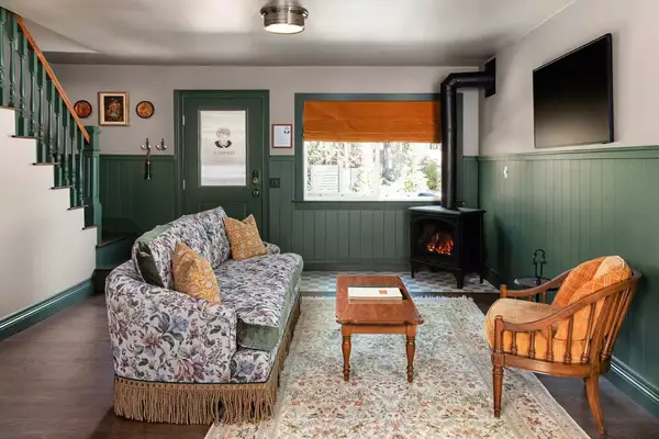 Cozy cabin interior decor, floral vintage couch and furniture with fireplace in the corner at Noble + Proper at Big Bear Lake in California