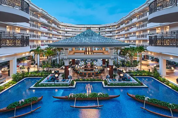 Luxurious hotel courtyard with a pool, pathway, lounge, and symmetrical balcony views under evening light