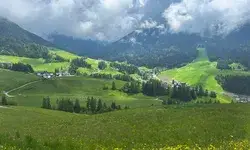Scenic view of a lush green valley with small villages surrounded by forested hills and mountains