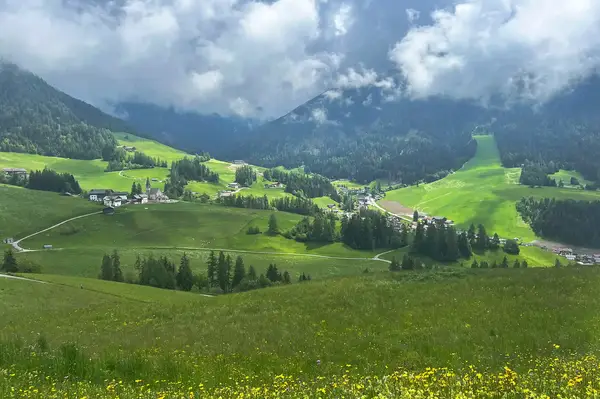 Scenic view of a lush green valley with small villages surrounded by forested hills and mountains