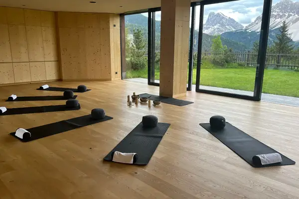 A yoga studio with mats and props set up large windows with a view of mountains and greenery