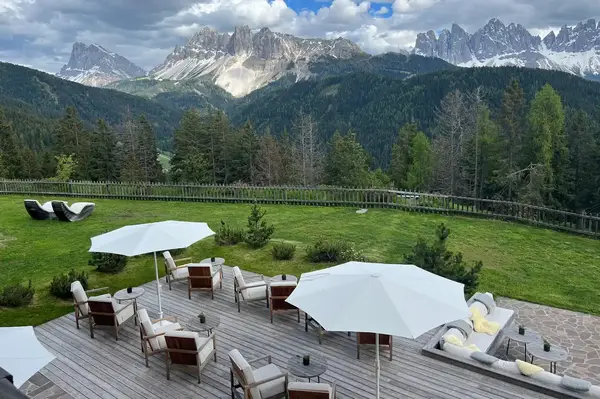 Outdoor seating area with umbrellas overlooking a mountainous forest landscape