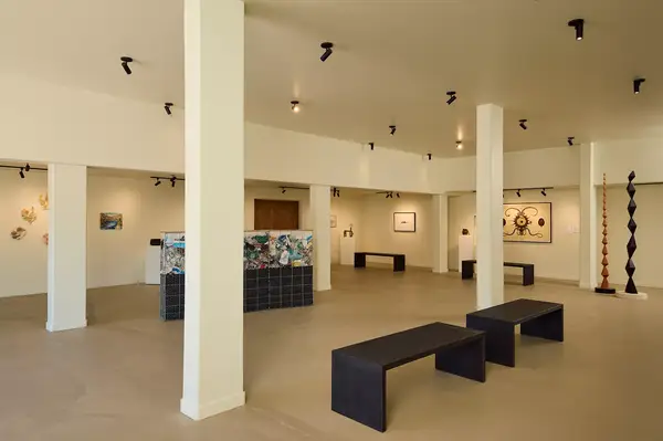 Interior of an art gallery with benches and artworks displayed on the walls and pedestal