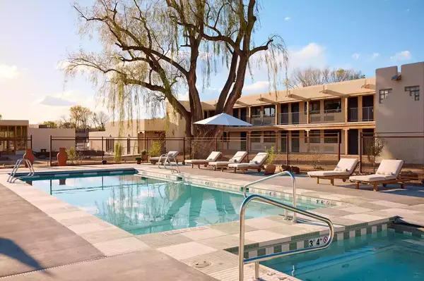 Outdoor hotel pool area with lounge chairs and umbrellas in a courtyard setting