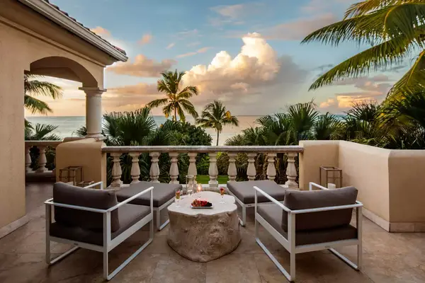 Two lounge chairs overlooking the beach and palm trees at sunset at Grace Bay Club