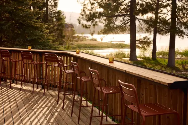 Deck area with bar stools overlooking a serene lake surrounded by trees