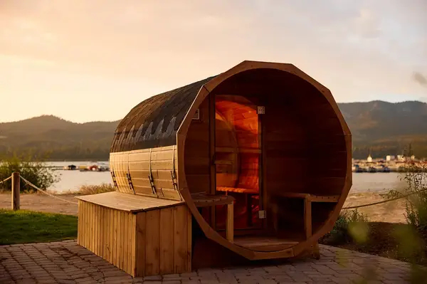 Barrel outdoor sauna by a lake at sunset
