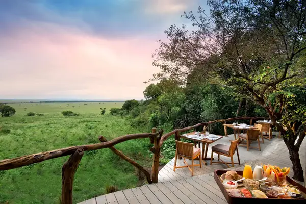 Outdoor dining area with tables and chairs overlooking a scenic grassy plain