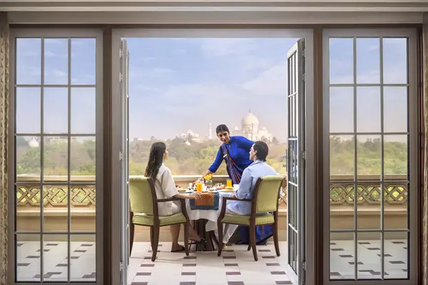 A couple has breakfast on a hotel terrace while speaking to a server